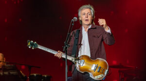 Paul McCartney spielt seinen ikonischen Höfner-Violinbass bei einem Konzert in den späten 1960er Jahren, eine Aufnahme in Schwarz-Weiß.