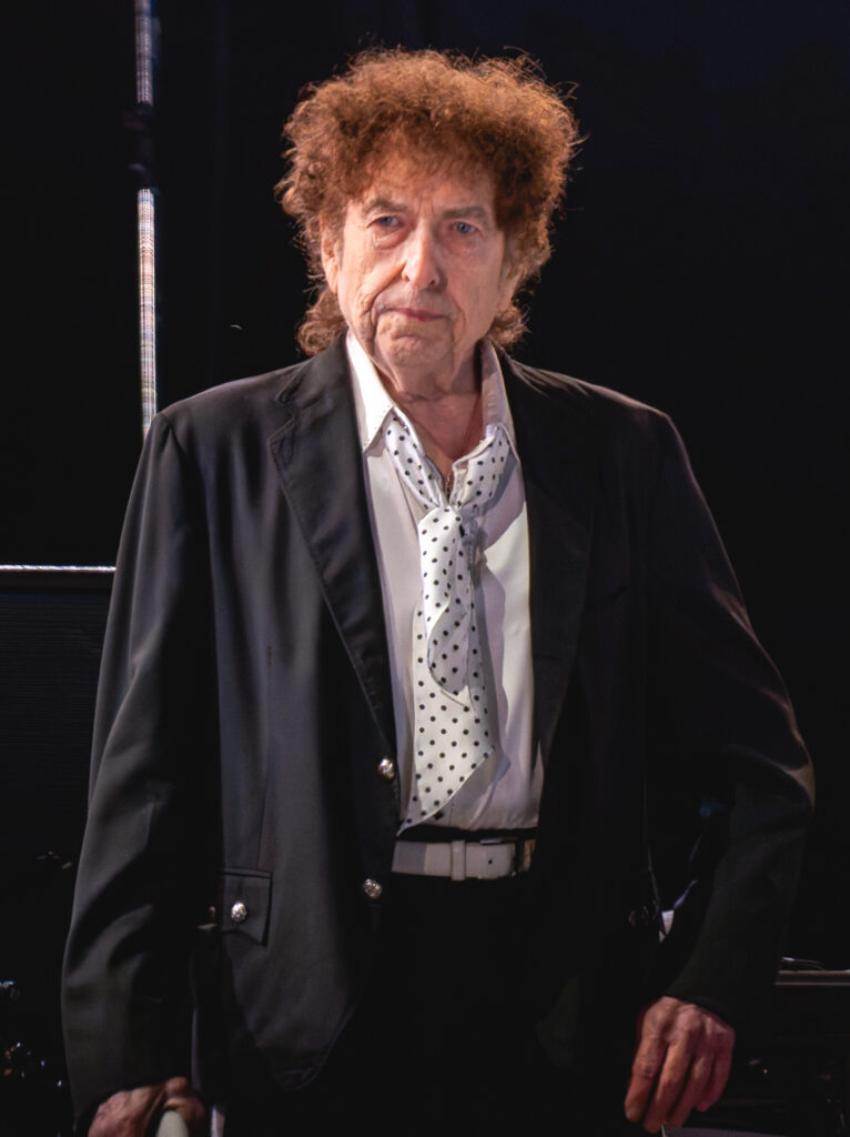 Bob Dylan mit Akustikgitarre und Mundharmonika während eines Auftritts in Greenwich Village, New York, um 1963.