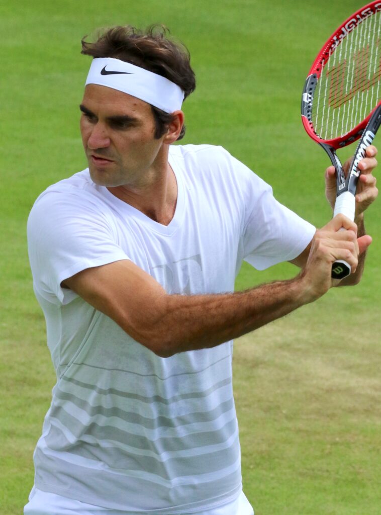 Roger Federer bei einem Aufschlag während der Wimbledon Championships, seine Bewegung in voller Streckung zeigend, um 2017.