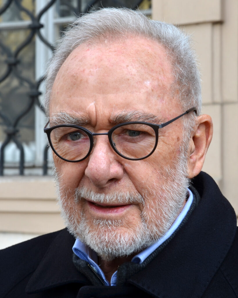 Der Künstler Gerhard Richter in seinem Kölner Atelier, umgeben von seinen großformatigen abstrakten Gemälden, nachdenklich blickend.