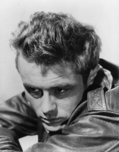James Dean in nachdenklicher Pose mit hochgeschlagenem Kragen, eine Zigarette im Mundwinkel, eine undatierte Aufnahme um 1955.