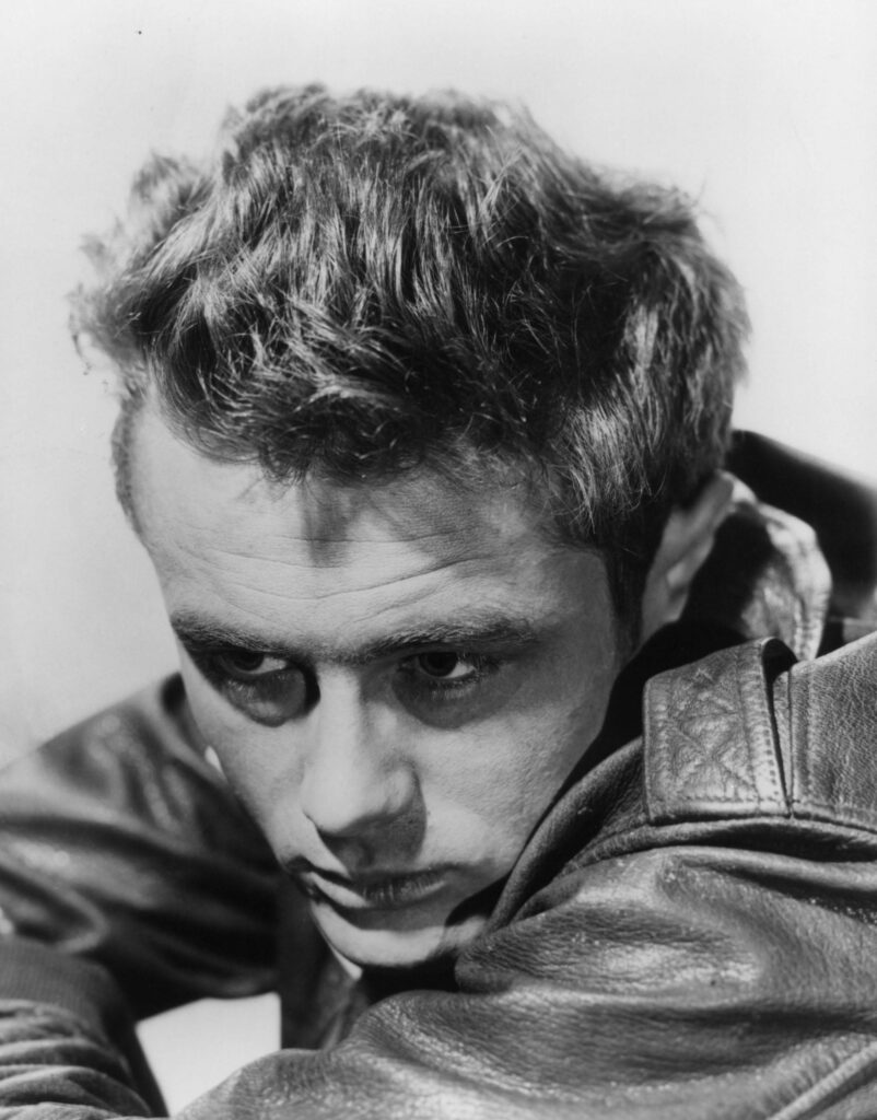 James Dean in nachdenklicher Pose mit hochgeschlagenem Kragen, eine Zigarette im Mundwinkel, eine undatierte Aufnahme um 1955.