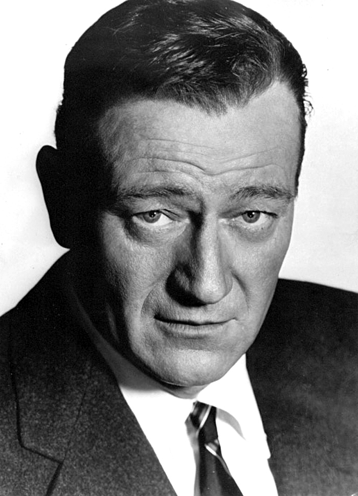 Der Schauspieler John Wayne in seiner Paraderolle als Westernheld, mit Cowboyhut und Halstuch, in einer Szene aus den 1950er-Jahren.