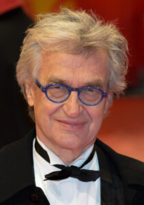 Filmregisseur Wim Wenders in einer nachdenklichen Pose, eine charakteristische Schwarzweißaufnahme des deutschen Autorenfilmers bei einem Festival.