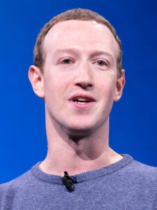 Mark Zuckerberg bei einer Konferenz, sprechend an einem Pult, im charakteristischen grauen T-Shirt, Aufnahme um 2018.