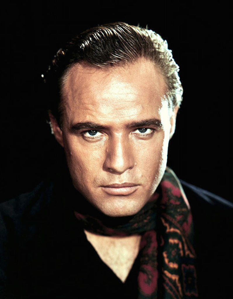 Marlon Brando als Johnny Strabler im Film 'Der Wilde' (1953), lässig auf seinem Motorrad sitzend, mit Lederjacke und Schirmmütze.