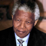 Nelson Mandela während einer Rede in den 1990er Jahren, mit einem charakteristischen Lächeln und in einem seiner bekannten bunten Hemden.