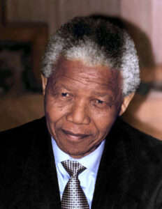 Nelson Mandela während einer Rede in den 1990er Jahren, mit einem charakteristischen Lächeln und in einem seiner bekannten bunten Hemden.
