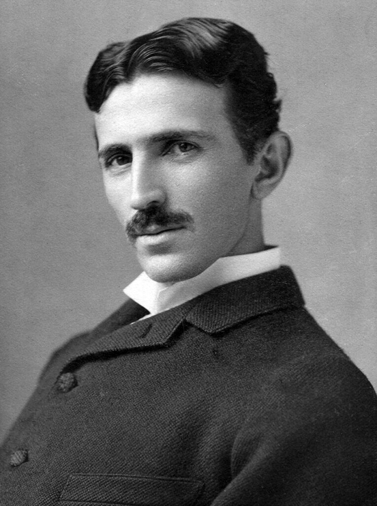 Nikola Tesla sitzt nachdenklich in seinem Labor in Colorado Springs, umgeben von Blitzen eines Tesla-Transformators, um 1899.
