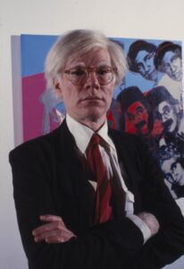 Andy Warhol mit seiner Polaroid-Kamera in den 1970er Jahren, eine typische Aufnahme des Künstlers, der das Flüchtige und Berühmte dokumentierte.