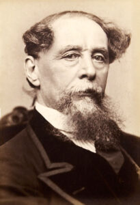 Der Schriftsteller Charles Dickens in einer Studioaufnahme um 1860, sitzend, mit nachdenklichem Blick und seinem charakteristischen Bart.