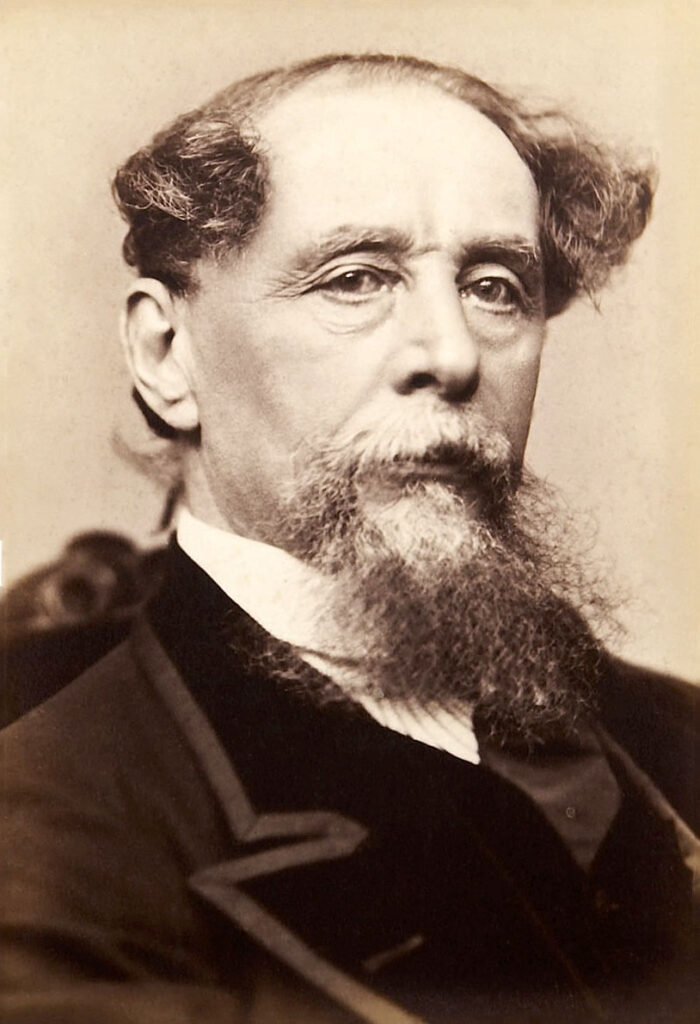 Der Schriftsteller Charles Dickens in einer Studioaufnahme um 1860, sitzend, mit nachdenklichem Blick und seinem charakteristischen Bart.