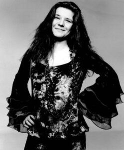 Janis Joplin bei einem Live-Auftritt um 1969, mit Mikrofon in der Hand und ihrer charakteristischen, leidenschaftlichen Mimik.