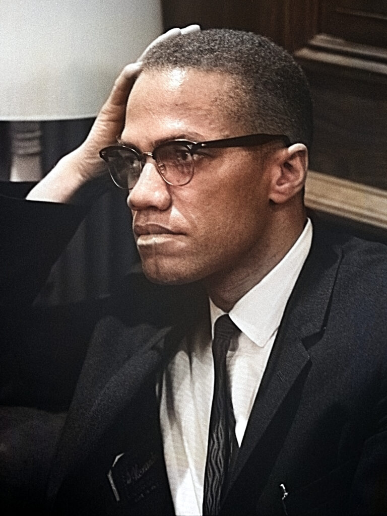 Malcolm X während einer Rede in Harlem, New York, um 1964, mit erhobenem Zeigefinger, in Anzug und Krawatte.