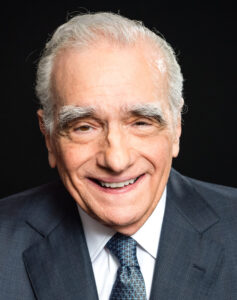 Der Regisseur Martin Scorsese am Set, mit konzentriertem Blick und gestikulierender Hand eine Szene für einen seiner Filme dirigierend.