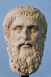 Eine Marmorbüste des Philosophen Platon, römische Kopie nach einem griechischen Original, die sein nachdenkliches Gesicht mit Bart und Stirnlocken zeigt.