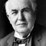 Thomas Alva Edison in seinem Labor in West Orange um 1911, neben einem Phonographen und chemischen Apparaturen.
