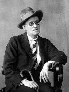 Der irische Schriftsteller James Joyce in einer Pariser Porträtaufnahme um 1920, mit charakteristischer Brille und ernstem Blick.