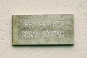 Die amerikanische Schriftstellerin Susan Sontag bei einer Lesung in den 1970er-Jahren, mit ernstem Blick und ihrer charakteristischen dunklen Haarsträhne.
