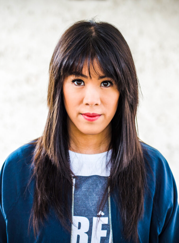 Die Wissenschaftsjournalistin Mai Thi Nguyen-Kim gestikuliert während eines Vortrags auf einer Bühne, im Hintergrund eine Projektion.
