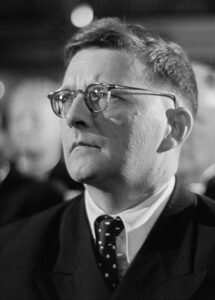 Dmitri Schostakowitsch am Klavier, konzentriert über eine Partitur gebeugt, aufgenommen in den 1940er Jahren in der Sowjetunion.