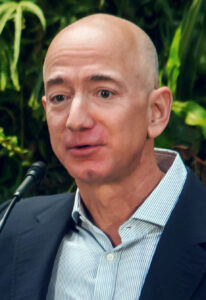 Der Unternehmer Jeff Bezos bei einer öffentlichen Veranstaltung, gekleidet in einem dunklen Anzug, mit nachdenklichem Ausdruck.