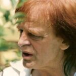 Klaus Kinski in einer nachdenklichen Pose während einer Drehpause, circa 1970er Jahre, das intensive Gesicht im Halbschatten.