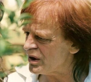 Klaus Kinski in einer nachdenklichen Pose während einer Drehpause, circa 1970er Jahre, das intensive Gesicht im Halbschatten.