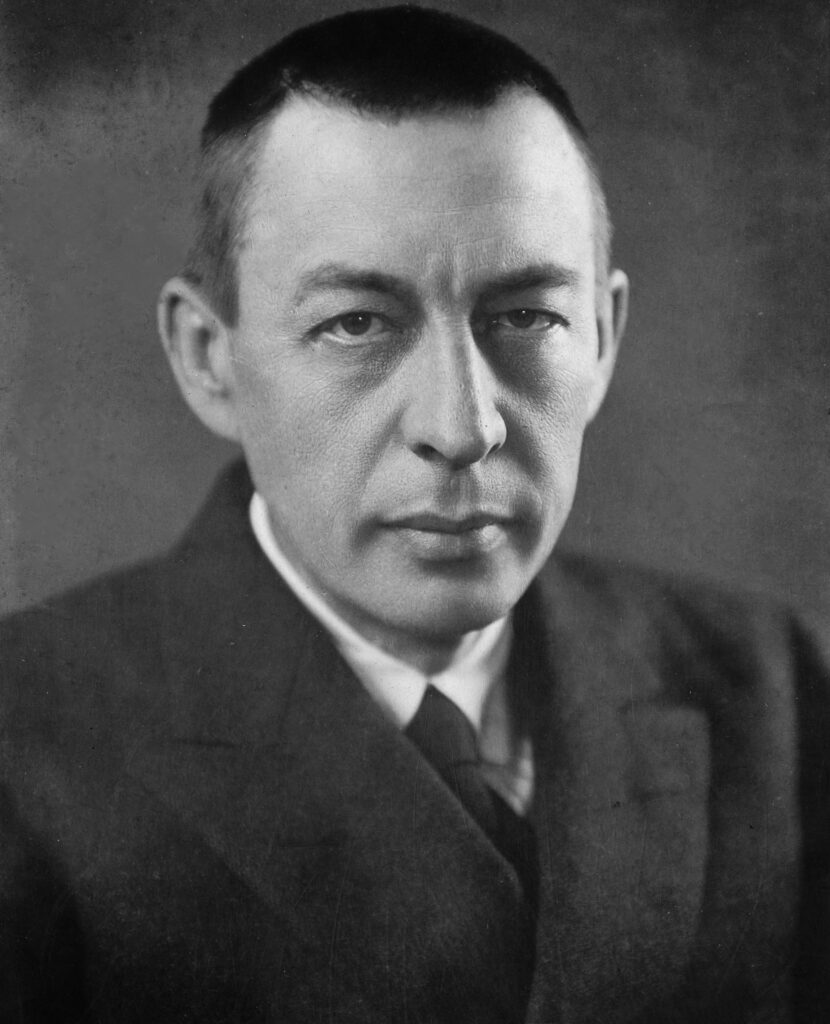 Sergei Rachmaninow in einer undatierten Aufnahme am Flügel, konzentriert auf die Partitur, die seine großen Hände umfassen.